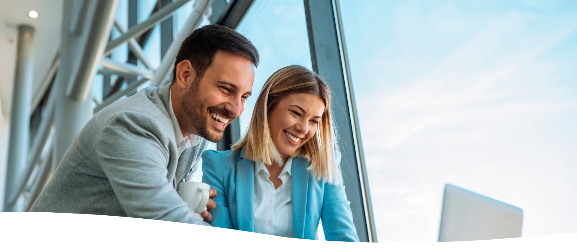 Hombre y mujer sonriendo mirando una computadora portátil